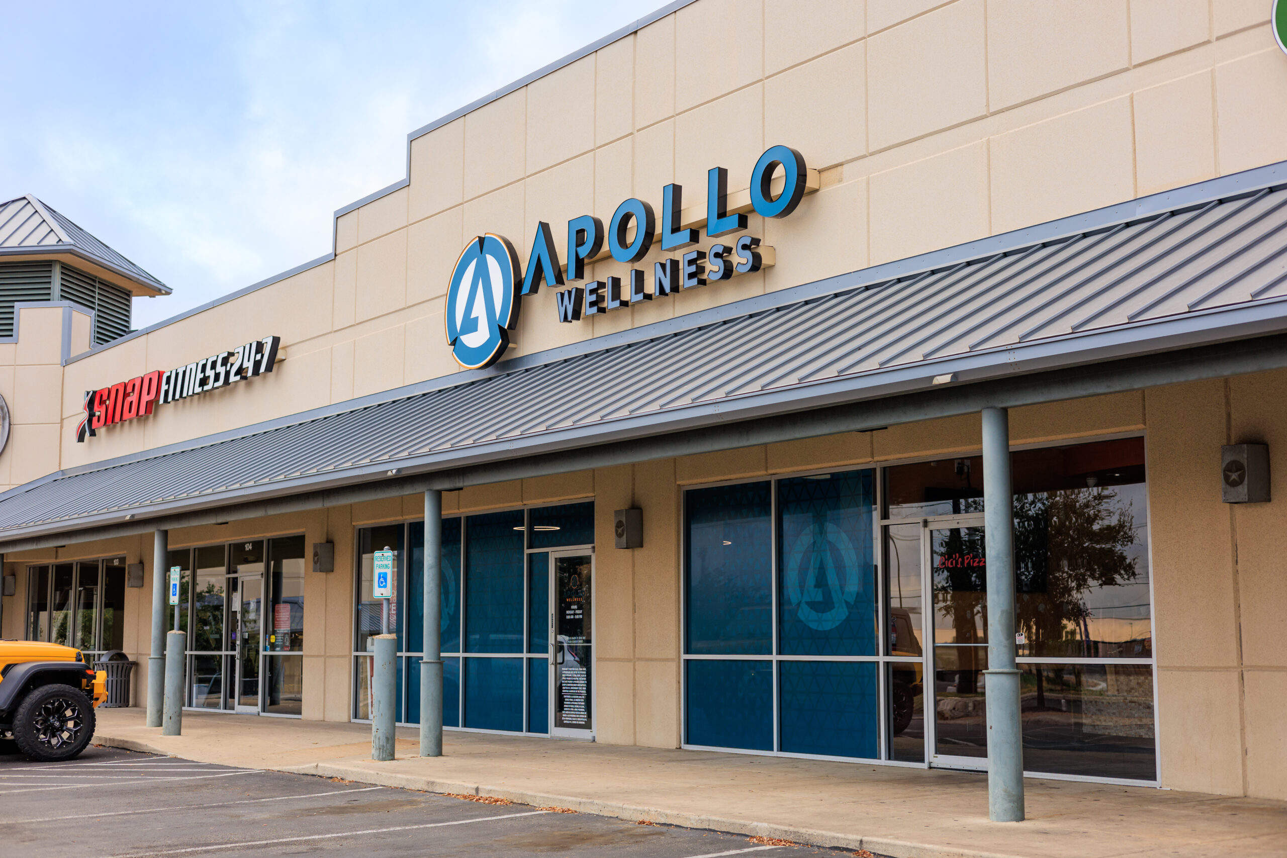 Apollo Wellness clinic entrance Front exterior of Apollo Wellness clinic in the Westwood Shopping center next to the Snap Fitness, showing the Apollo Wellness clinic’s name and logo, front door entrance, and window decal for privacy.